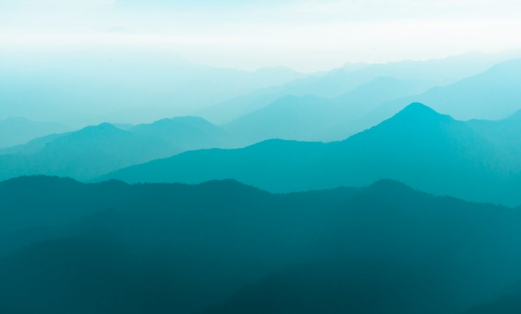 Misty blue mountain layers fading into the horizon under a bright sky.